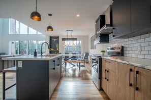 A modern kitchen with a central island, pendant lighting, and a view of the outdoors.