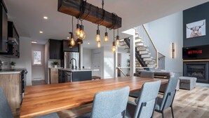 A modern kitchen with a wooden island, pendant lights, and a staircase leading to a loft. - Scandinavian chalet | SPA and Pool Table | Le 70 (Lanaudière)