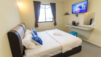 A bedroom with a bed, a television, a window with curtains, and a small table with a cup.