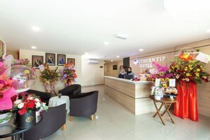 A hotel reception area with a desk, chairs, and floral decorations. - Southern TIP Hotel (Pontian District)