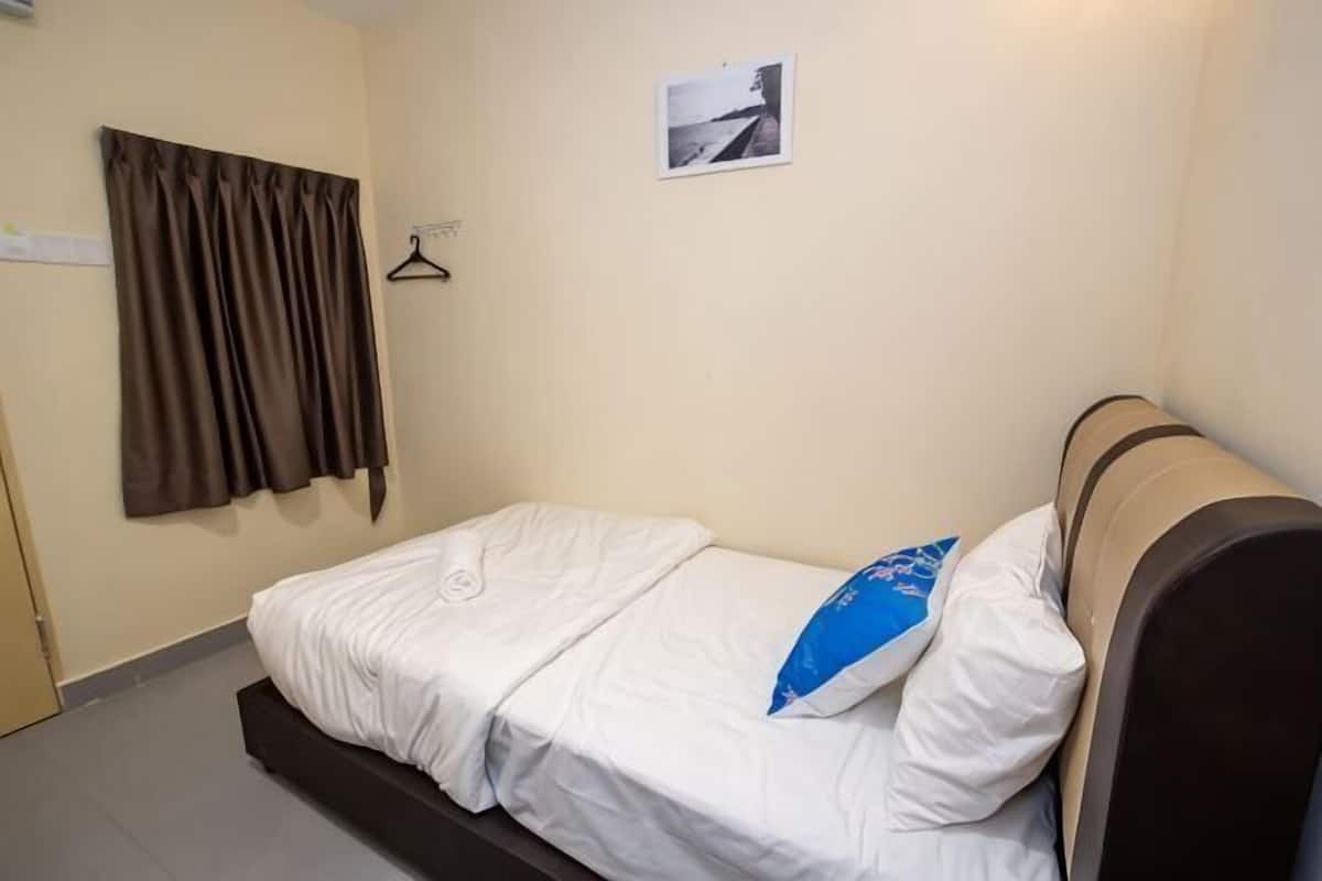 A single bed with a headboard, a hanging curtain, and a small picture on the wall.