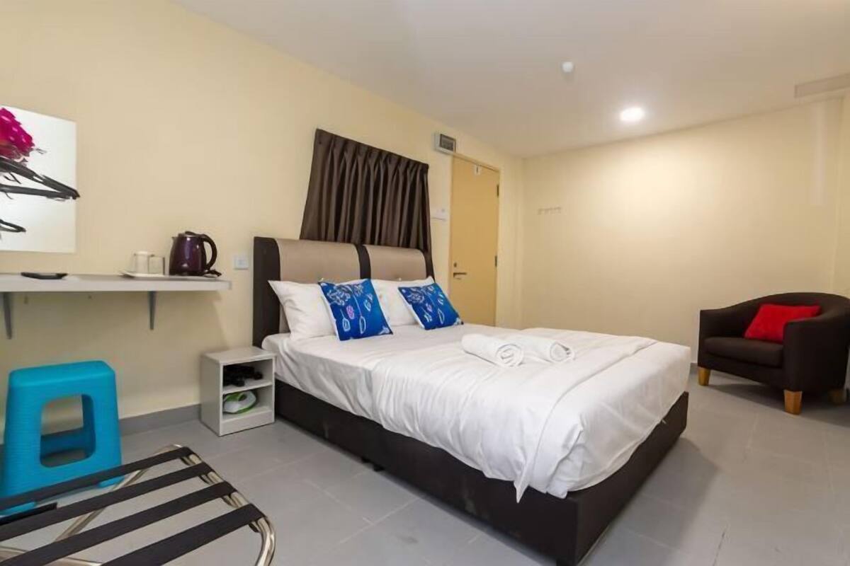 A bedroom with a bed, a nightstand, a chair, and a desk with a chair.