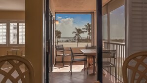 A balcony with a view of the beach, palm trees, and a sailboat. - Beachfront 2B/2B Sandarac Vacation Condo - Million Dollar Gulf View! (Fort Myers Beach)