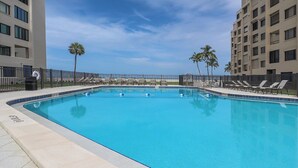 A rectangular swimming pool with a tiled edge, surrounded by a low fence and lounge chairs. - Beachfront 2B/2B Sandarac Vacation Condo - Million Dollar Gulf View! (Fort Myers Beach)