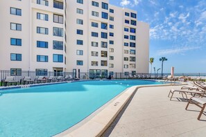 Un hôtel doté d’une grande piscine, de chaises longues et offrant une vue dégagée sur l’océan.