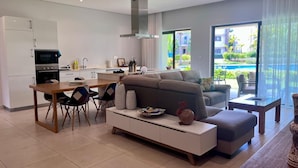 Una sala moderna con sofá, mesa de comedor y zona de cocina.