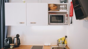 A kitchenette with a microwave, kettle, toaster, and a small sink. - Apartments Haus Altenberger 1 Studio (Zell am See)
