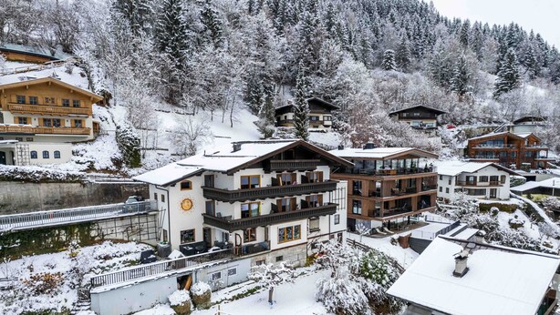 A snow-covered resort with multi-story buildings, a ski lift, and a lake. - Apartments Haus Altenberger 1 Studio (Zell am See)