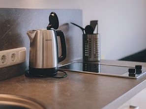 A kitchen counter with a stainless steel Philips electric kettle, a power strip, and a utensil holder.