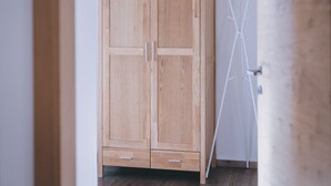 A wooden wardrobe with two doors and two drawers, positioned in a hallway with a white wall and a wooden floor. - Apartments Haus Altenberger 3 Bergblick (Zell am See)