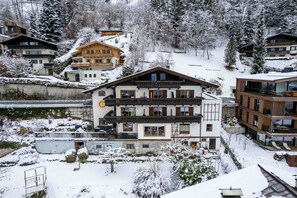 A multi-story hotel with balconies, a ski slope in the background, and snow-covered surroundings.