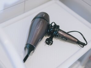 A hair dryer with a cord and a plug on a white surface.