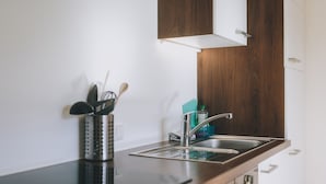 A modern kitchen with a stainless steel sink, wooden cabinets, and a black countertop. - Apartments Haus Altenberger 4 Seeblick (Zell am See)