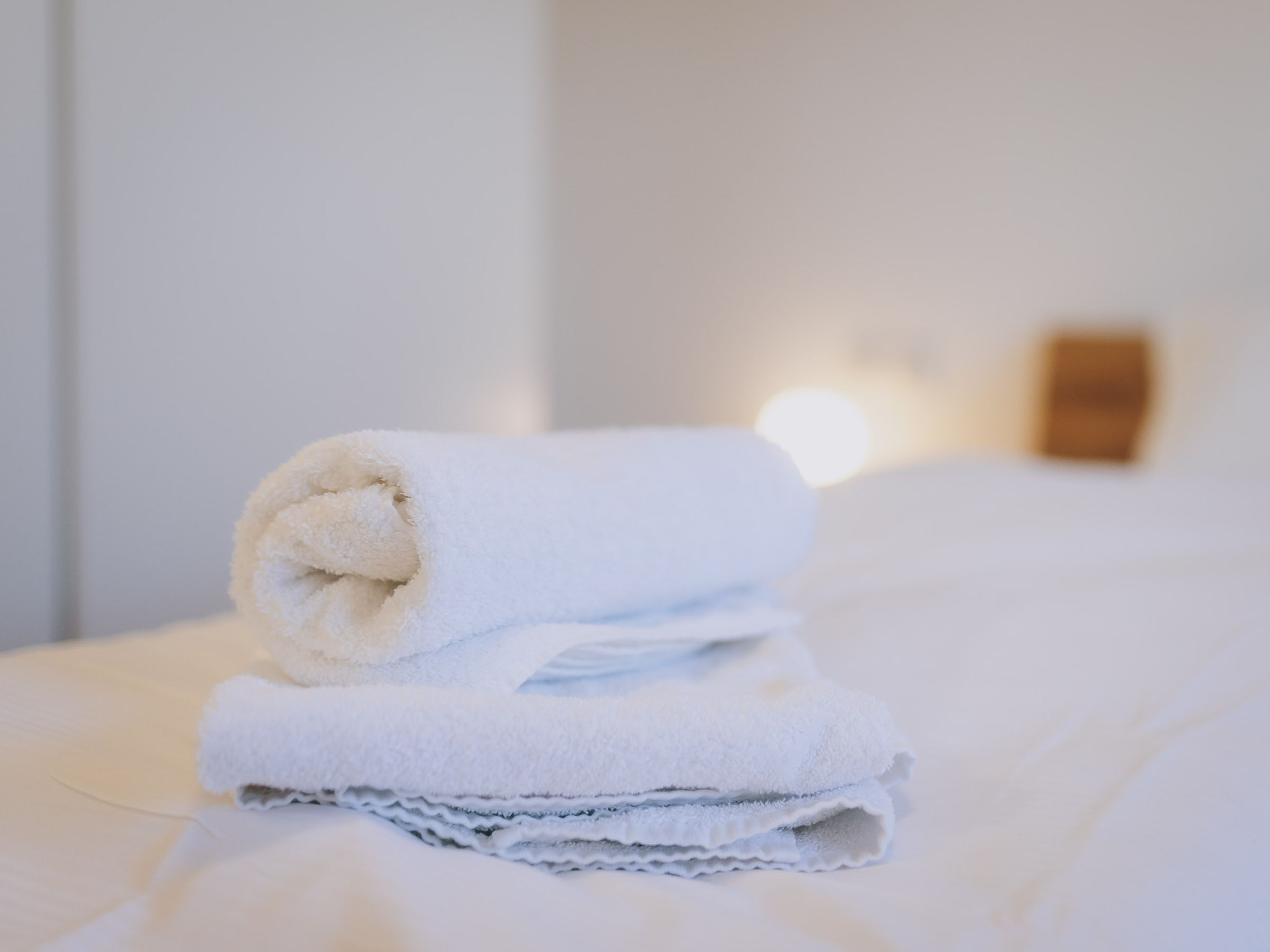 Ein ordentlich gefaltetes weißes Handtuch auf einem Bett in einem Hotelzimmer.
