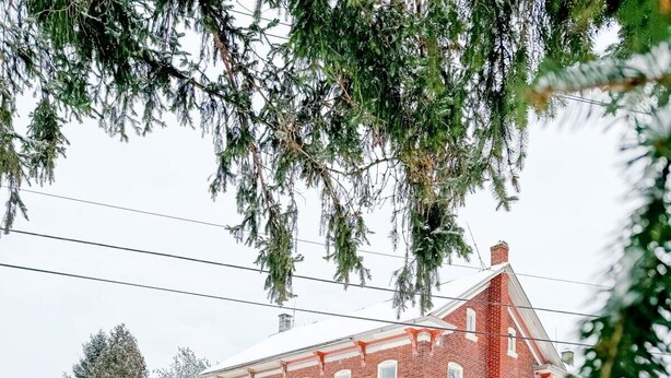 Un edificio de ladrillo rojo con un porche y un paisaje cubierto de nieve.