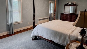Un dormitorio con una cama grande, un aparador, un espejo y una lámpara.