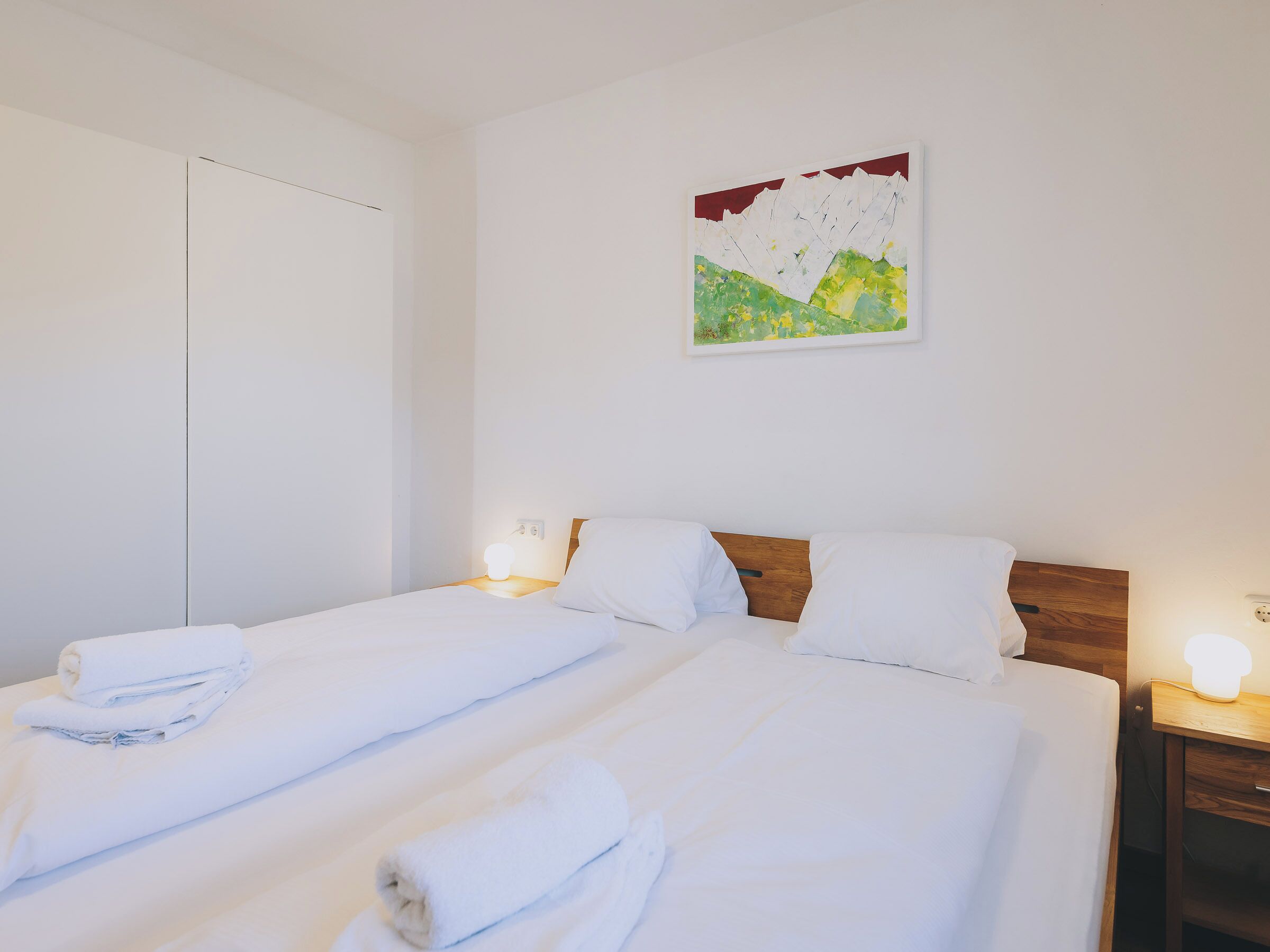 Ein Hotelzimmer mit einem Bett, zwei Nachttischen und einem an der Wand befestigten Kunstwerk.