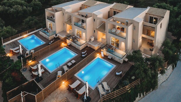 Un edificio moderno de varios pisos con dos piscinas, mobiliario exterior y un jardín ajardinado.