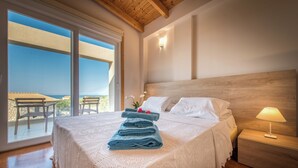 Un dormitorio con una cama grande, una mesita de noche, una lámpara y vistas al exterior.