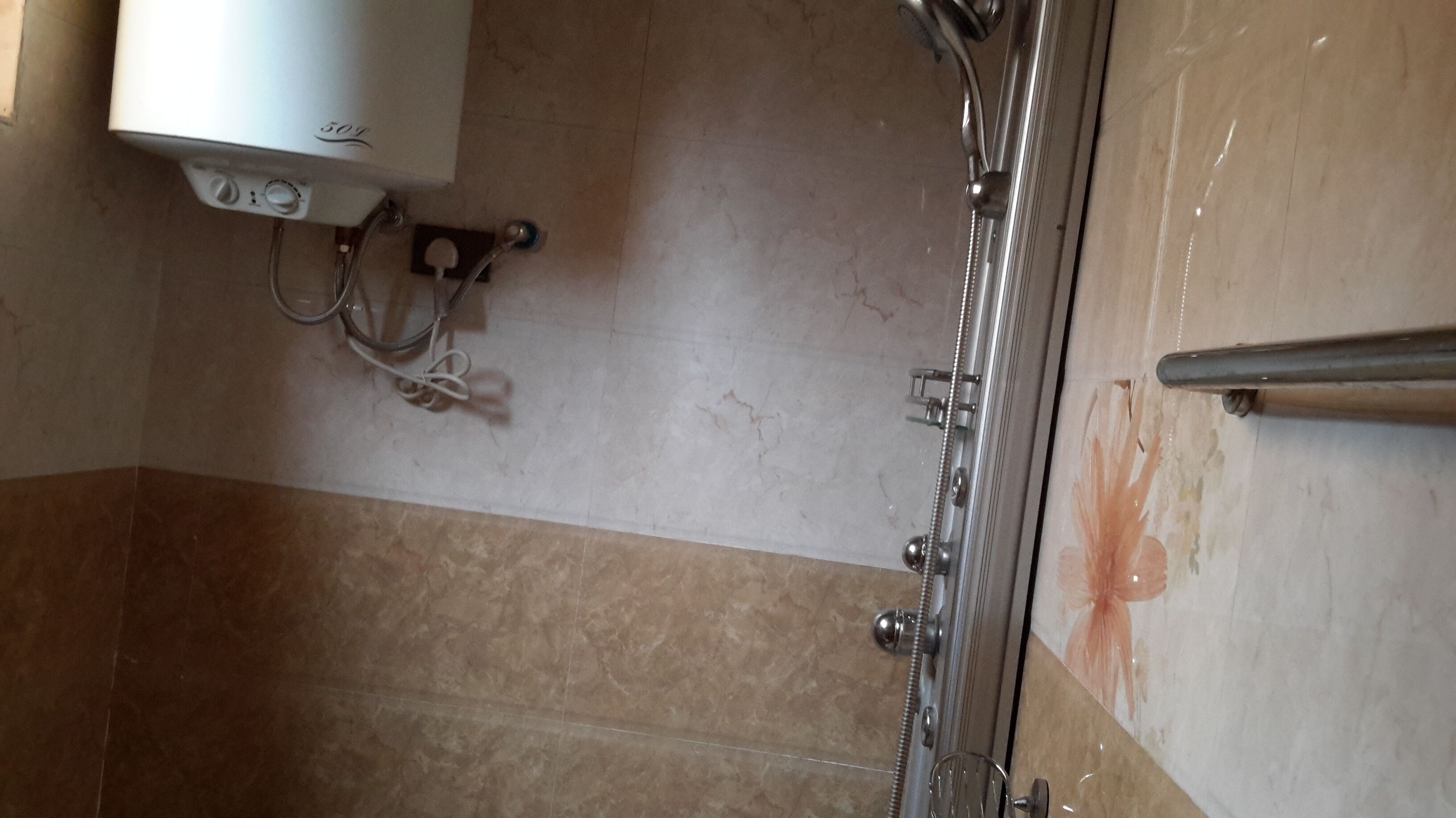 A bathroom with a shower, a toilet, and a wall-mounted heater.