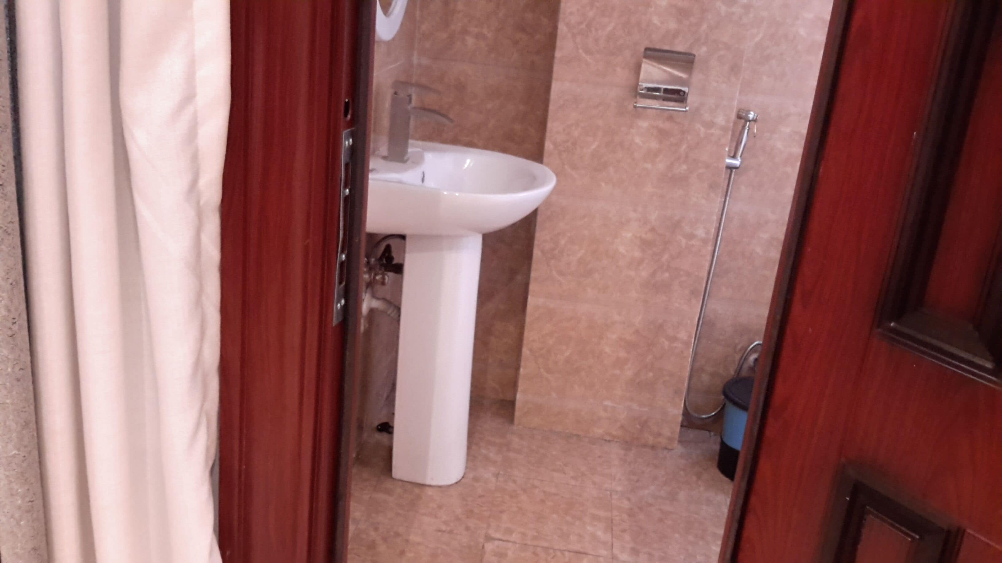 A bathroom with a white sink, a shower, and a tiled floor.
