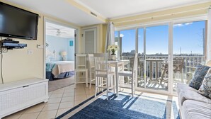 Ein geräumiger Wohnbereich mit Balkon, Fernseher und Esstisch.
