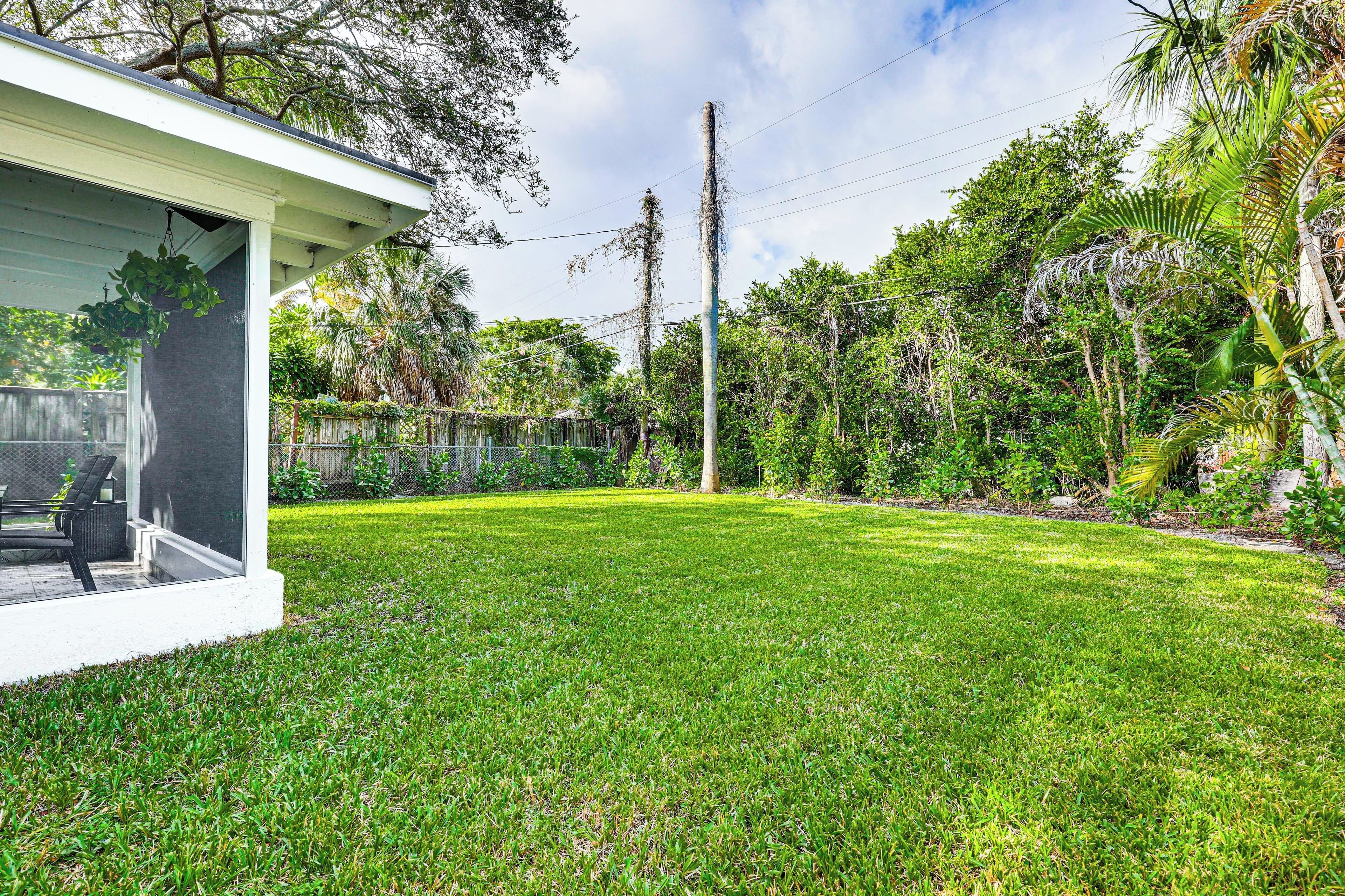 A well-maintained lawn with a patio area and a house with a covered porch.