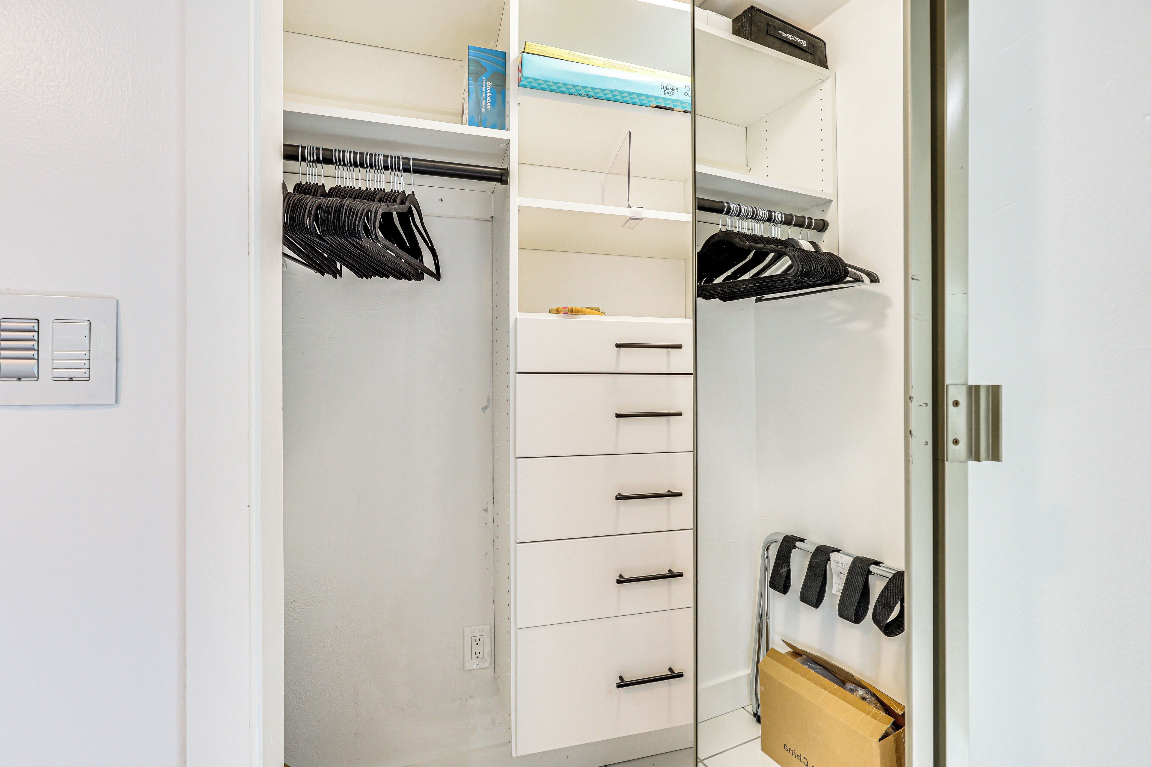 A walk-in closet with hanging space, drawers, and shelves.