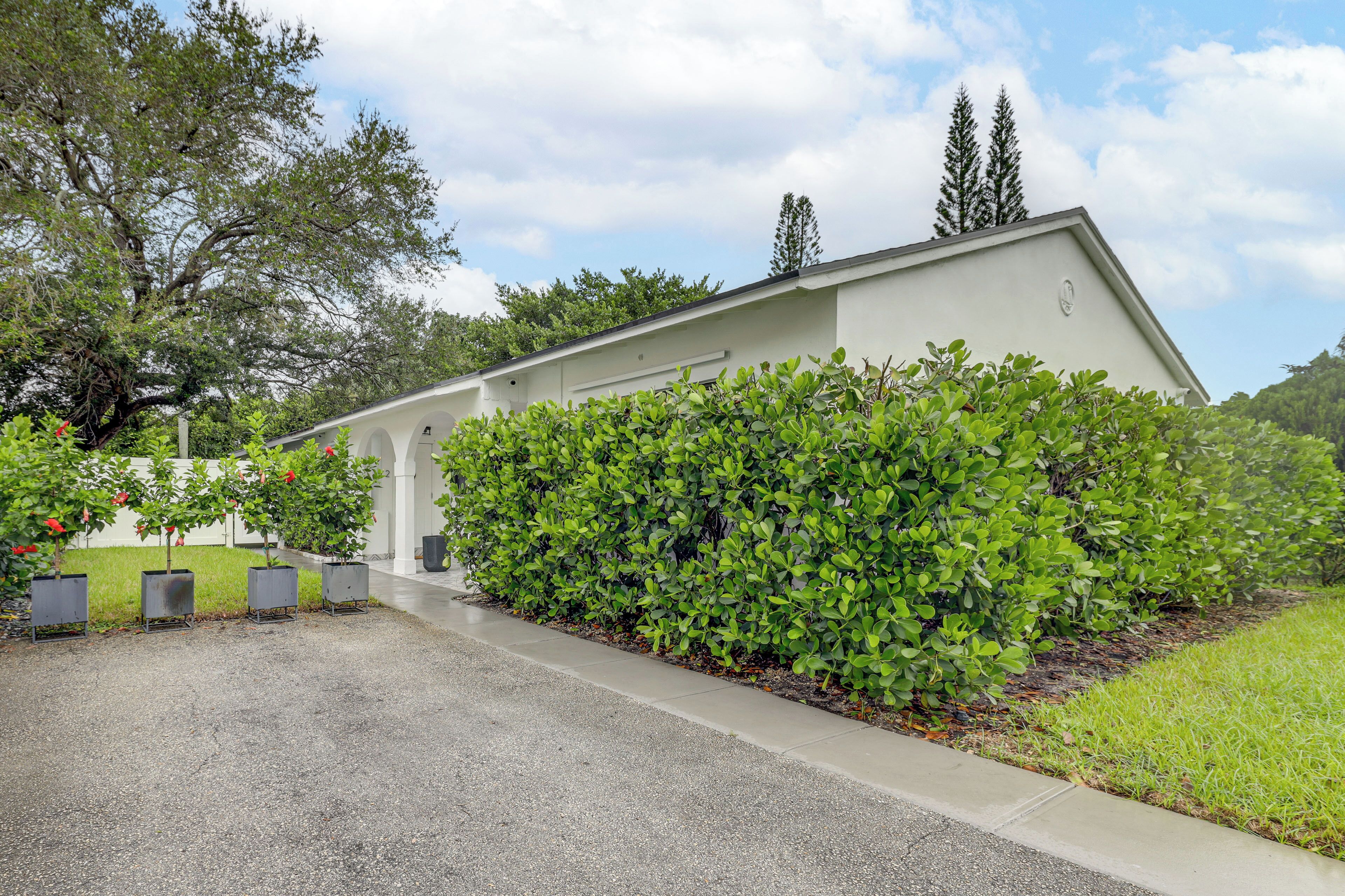A building with a flat roof, a paved entrance, and a well-maintained hedge.
