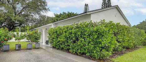 A building with a flat roof, a paved entrance, and a well-maintained hedge.