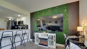 Eine moderne Küche mit Einbau-Mikrowelle, Kühlschrank und Kaffeemaschine. Es gibt eine Sitzecke mit Sofa und Esstisch.