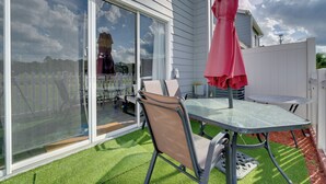 Eine Terrasse mit Glastür, Tisch, Stühlen und einem roten Sonnenschirm.