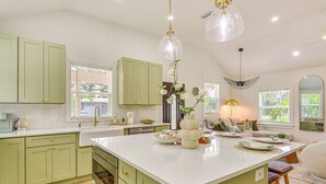A kitchen with green cabinets, a white island, and pendant lights. - Pool, Mini Golf & Cabana: Bradenton Retreat (Bradenton)
