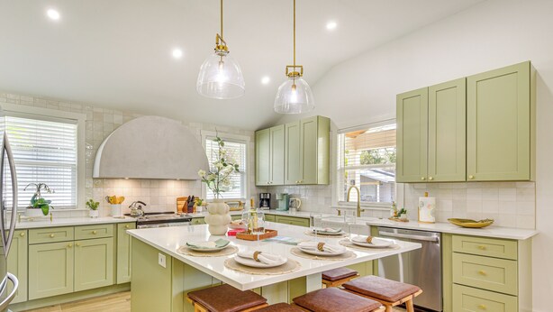 A modern kitchen with green cabinets, a central island with stools, and pendant lighting. - Pool, Mini Golf & Cabana: Bradenton Retreat (Bradenton)