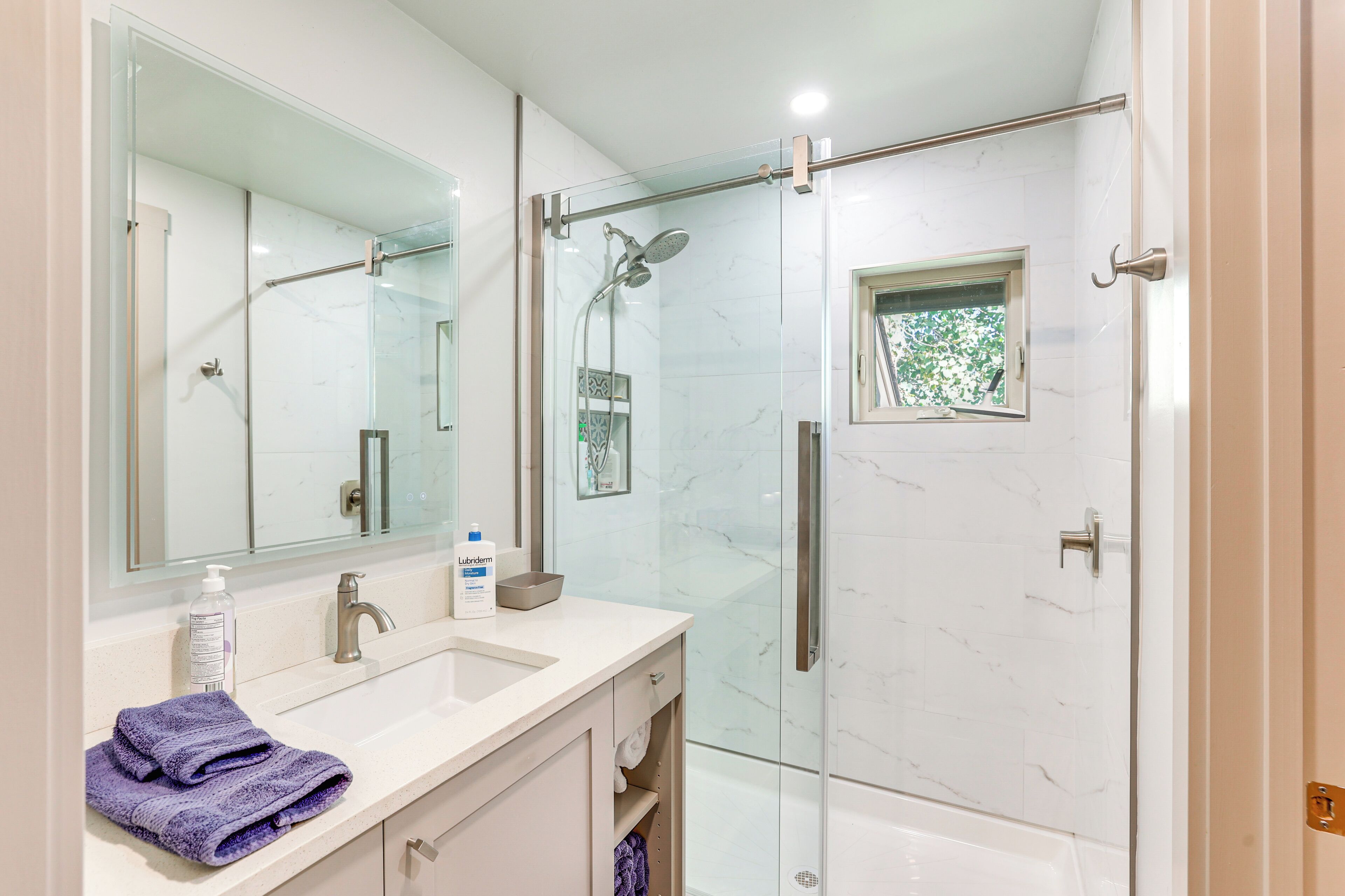 A bathroom with a glass-enclosed shower, a sink with a mirror, and a towel on the counter.