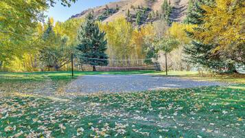 A park with a volleyball net, trees, and a mountain in the background.