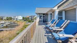 Een houten terras met lounge fauteuils met uitzicht op een jachthaven.