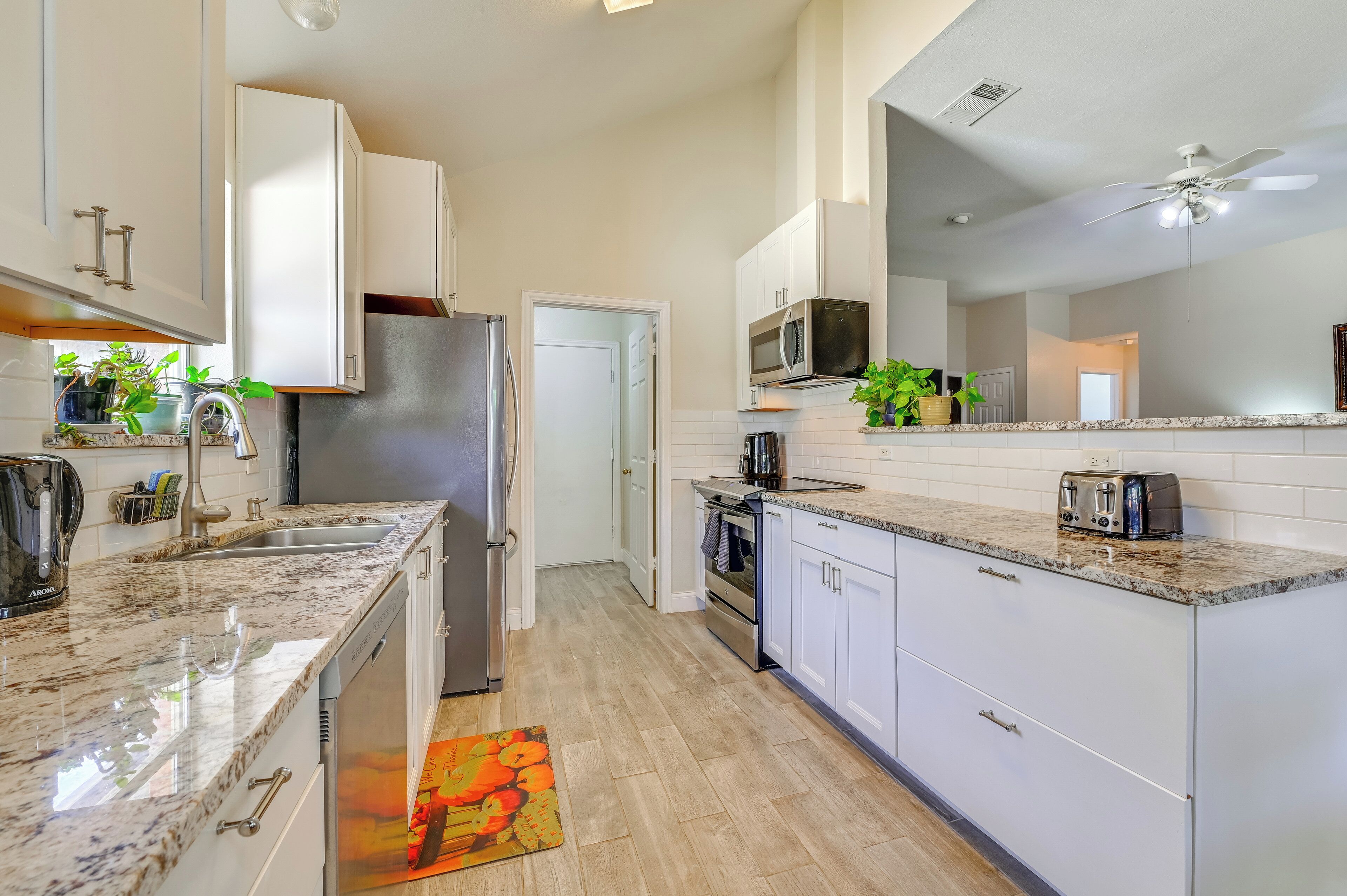 A modern kitchen with white cabinets, a stainless steel refrigerator, a microwave, and a toaster.
