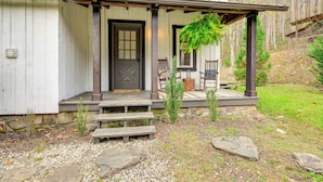 A rustic cabin with a wooden door, a porch with benches, and a stone foundation. - Fish & Water Raft: Cabin Near Lake Santeetlah (Robbinsville)