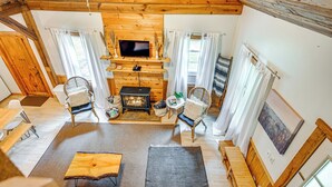 A cozy wooden cabin interior with a fireplace, comfortable seating, and a television. - Fish & Water Raft: Cabin Near Lake Santeetlah (Robbinsville)