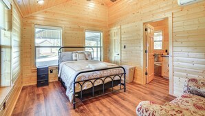 Dormitorio de cabaña de madera con una cama, un ventilador de techo y una ventana.