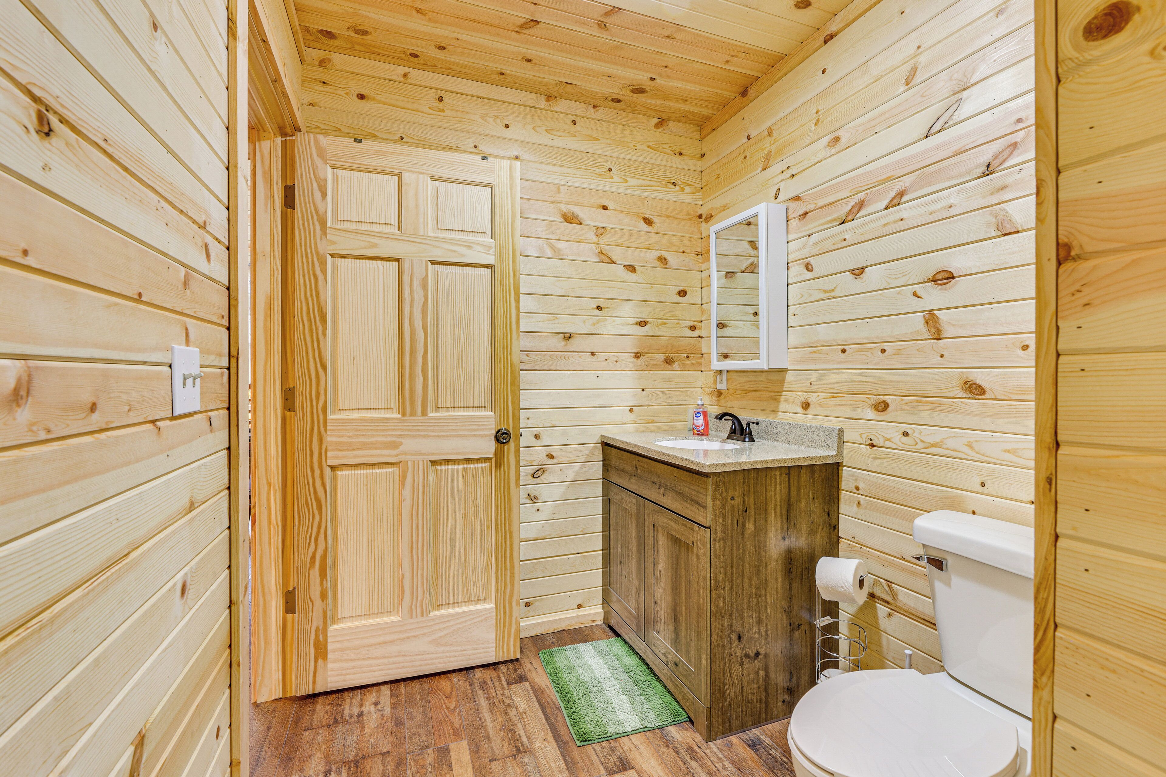 A wooden-paneled bathroom with a toilet, sink, and mirror.