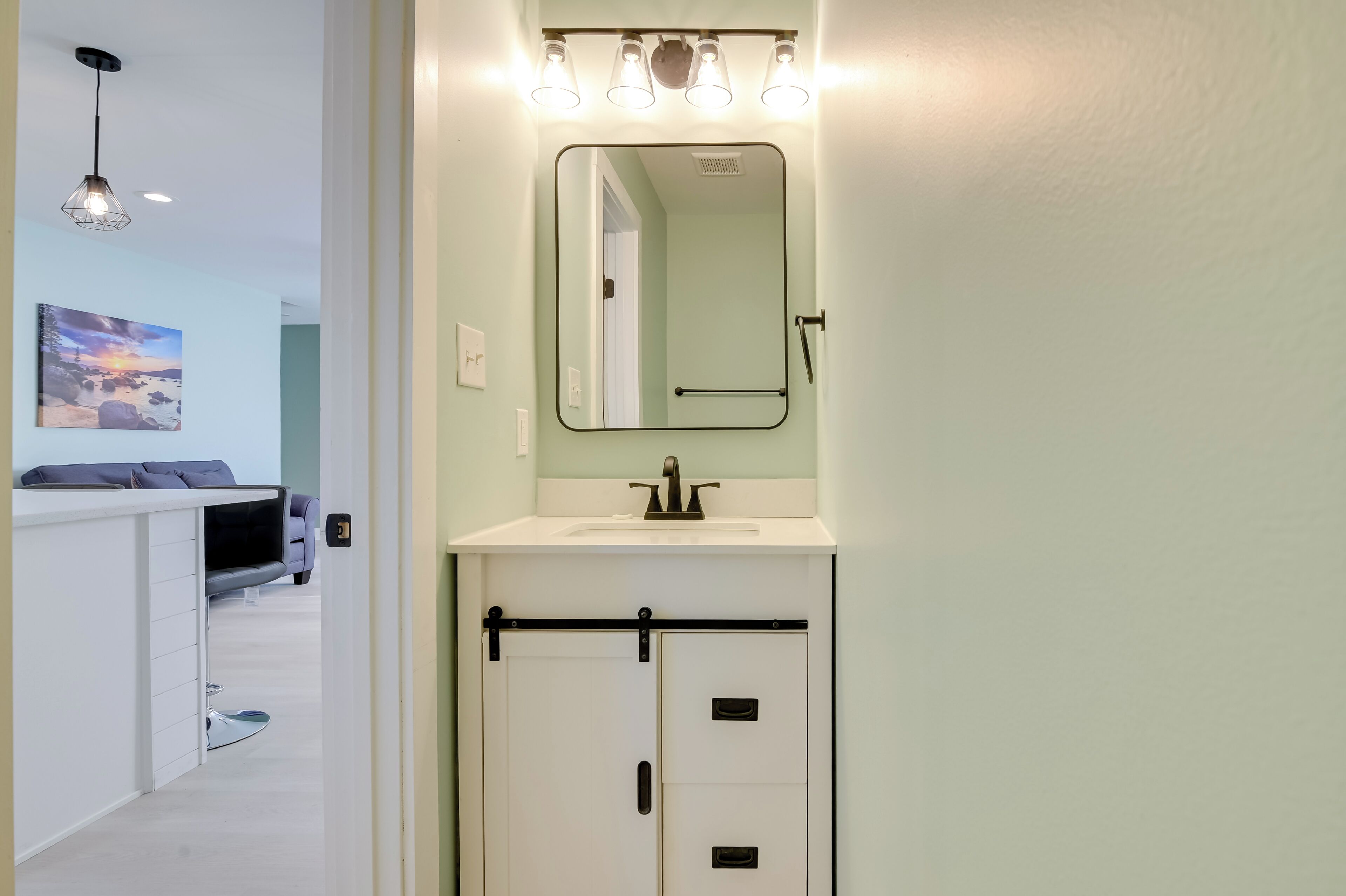 A bathroom with a white sink, a mirror, and a towel rack.