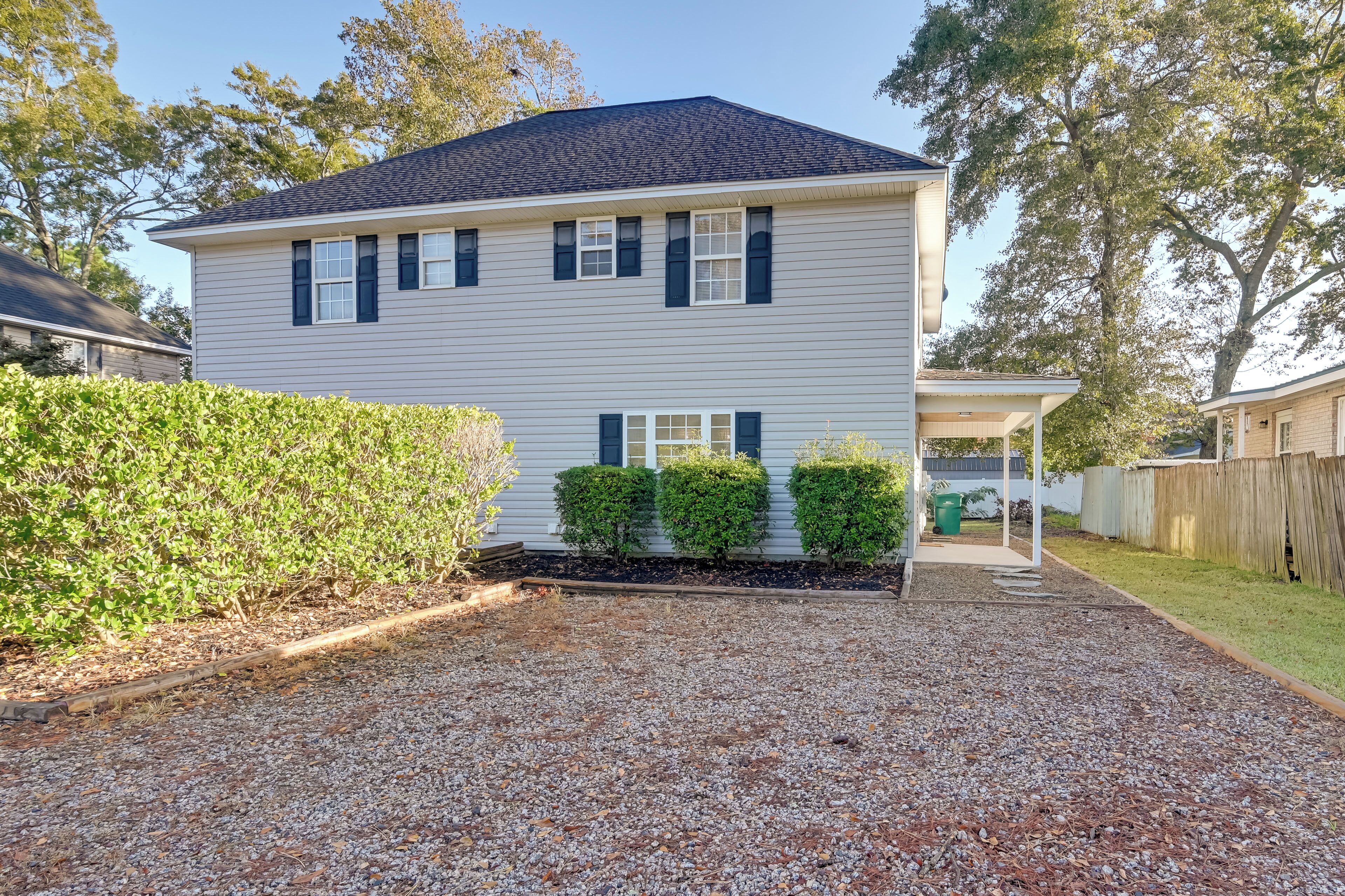 A two-story house with a gravel driveway and a covered porch.