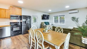 A compact kitchen with a dining table, chairs, a microwave, a refrigerator, and a TV mounted on the wall. - Lake-view Home in Statham w/ On-site Fishing (Statham)