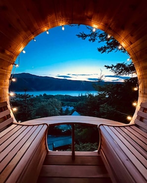 A wooden structure with a curved roof and a bench inside, overlooking a lake and mountains. - Lodges On Loch Ness (Inverness)