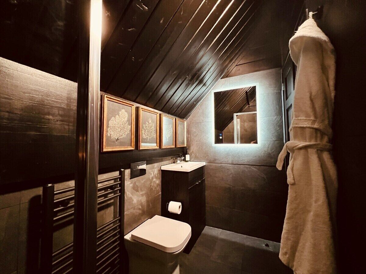 Ein kleines Badezimmer mit Toilette, Waschbecken und Spiegel. Ein Handtuch hängt an der Wand.
