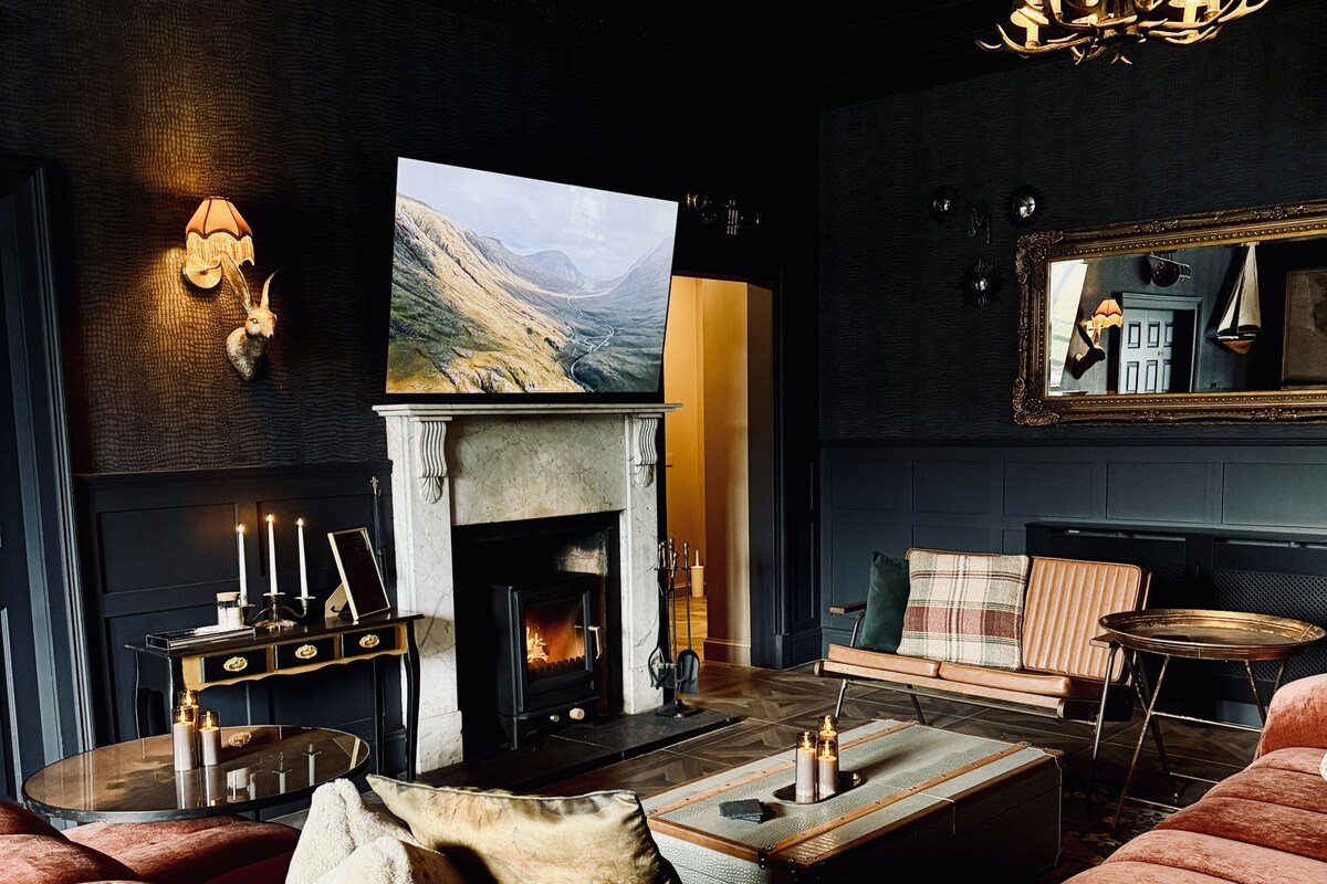 A cozy living room with a fireplace, a television mounted above it, and a comfortable seating area with plush sofas and a coffee table.