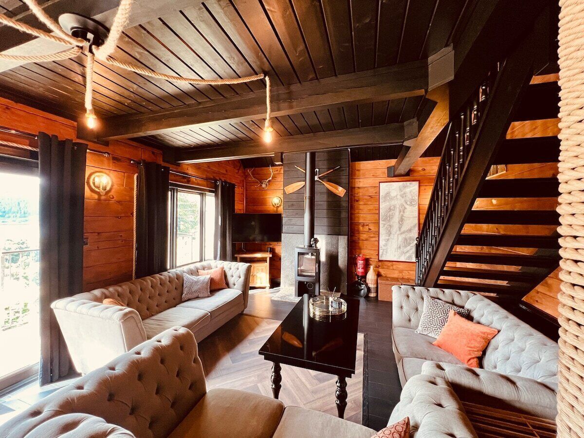 A cozy living room with a fireplace, two sofas, a coffee table, and a staircase.
