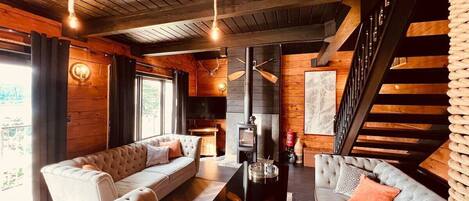 A cozy living room with a fireplace, two sofas, a coffee table, and a staircase.